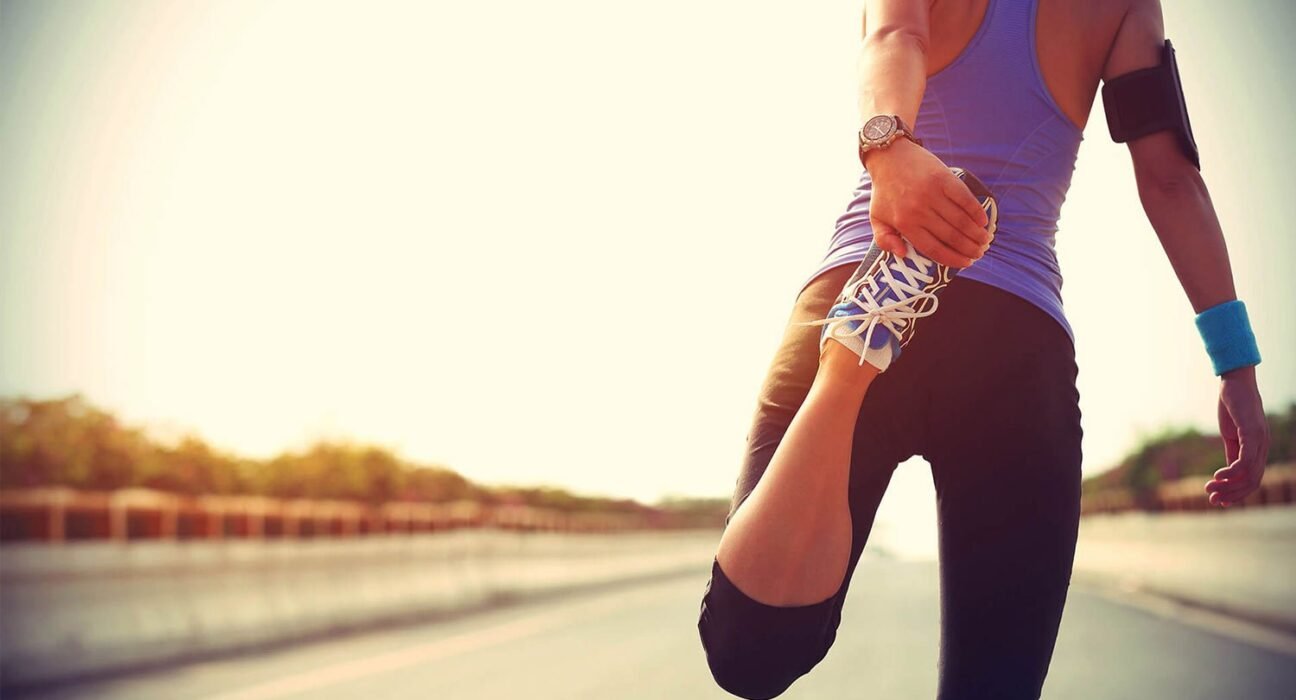 find more africa #findmoreafrica › Runner on an open road ties a blue-and-white sneaker, preparing for a run at sunset.