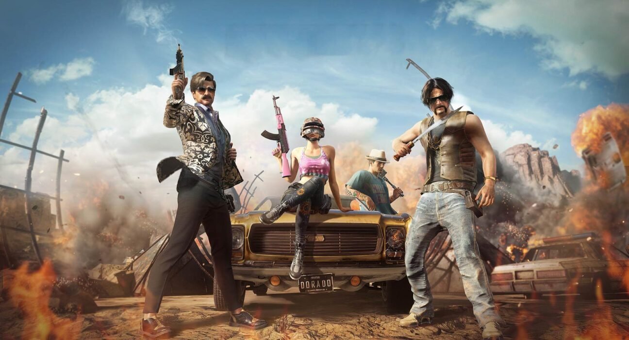 Four rugged survivors pose with guns in a desert battlefield, a damaged car in the foreground and smoke and flames around.