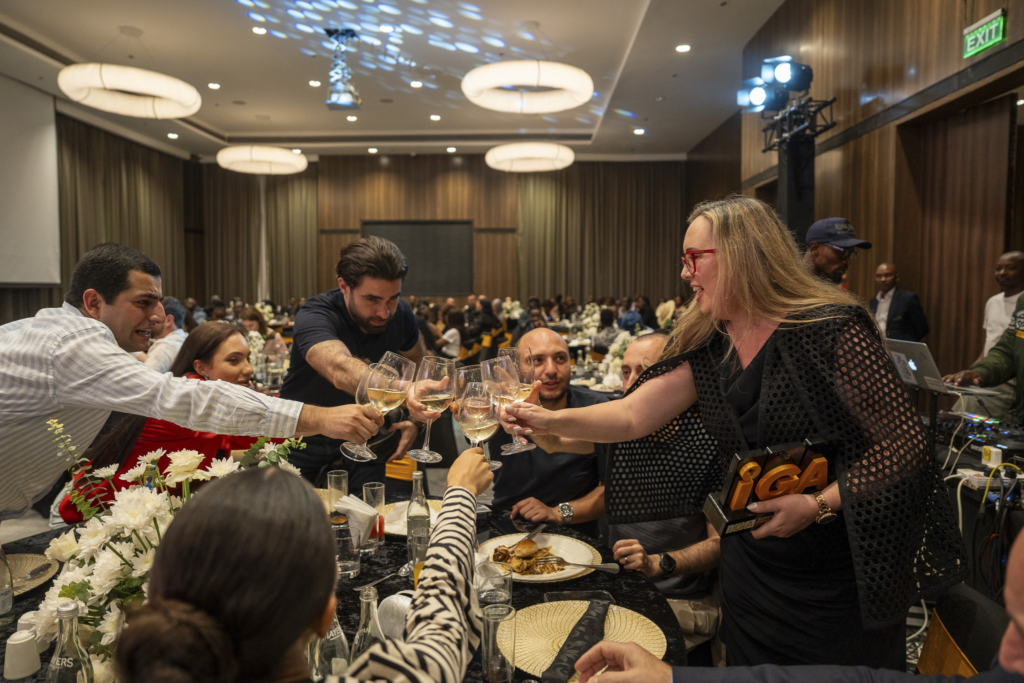 find more africa #findmoreafrica › Guests raise wine glasses in a toast around a decorated banquet table in a hotel ballroom.
