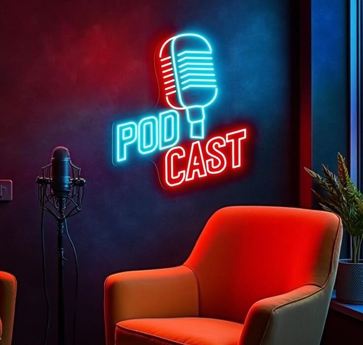 Neon 'PODCAST' sign in blue and red with a retro microphone graphic on a dark wall, a red chair in the foreground, and a mic stand nearby.