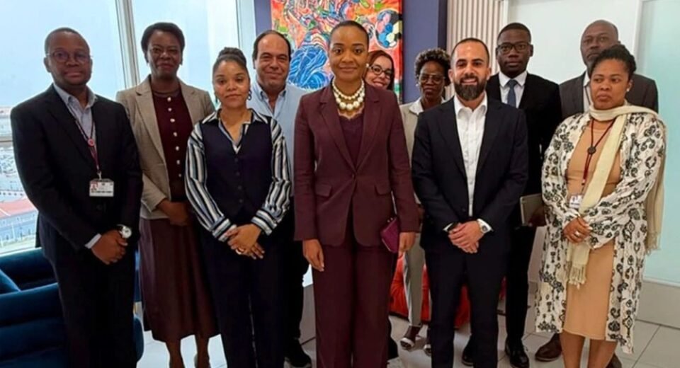 Group of ten professionals in business attire posing for a photo in a modern office with a colorful abstract painting behind them.