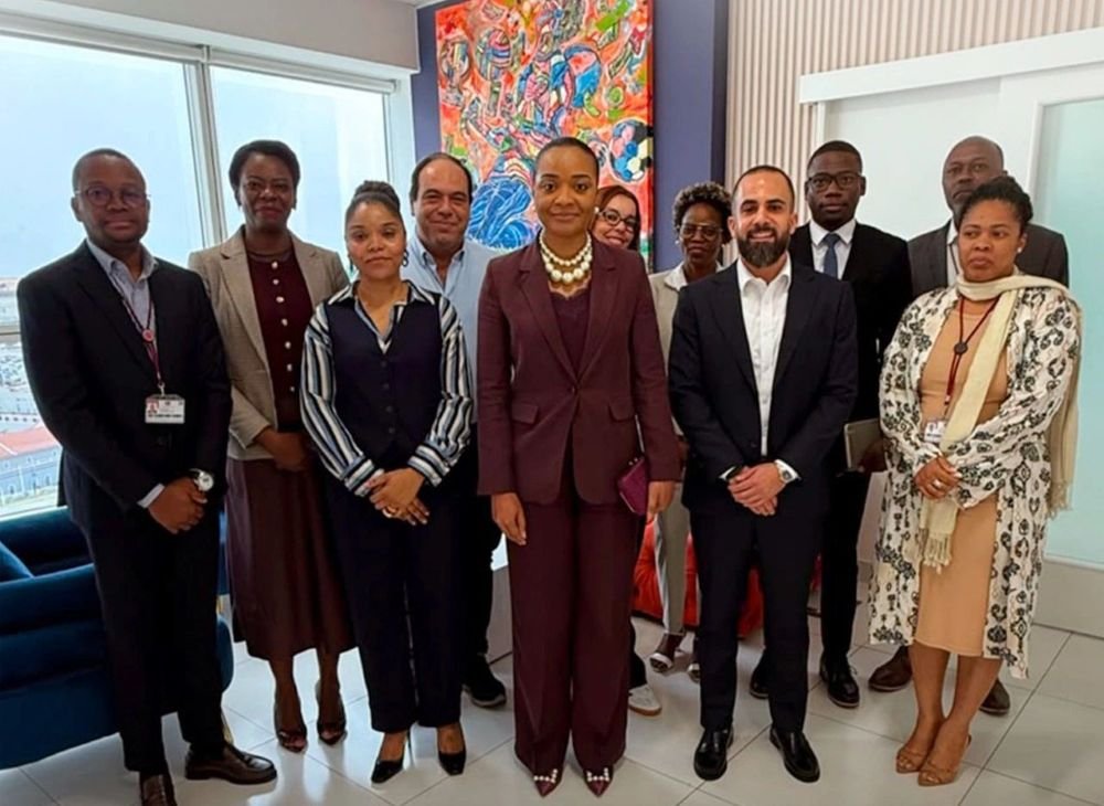 Group of ten professionals in business attire posing for a photo in a modern office with a colorful abstract painting behind them.