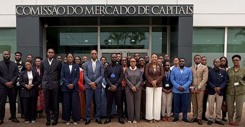 Diverse group of professionals posing for a formal group photo outside a building labeled 'Comissão do Mercado de Capitais'.