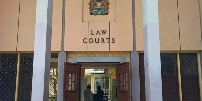 Entrance to a law courts building with the sign 'LAW COURTS' above double wooden doors, two people entering.
