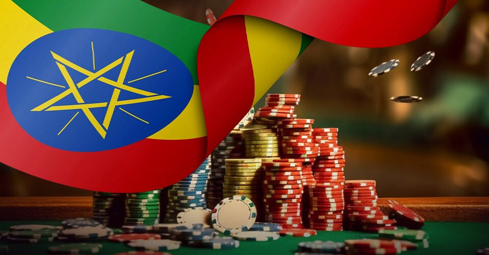 Stacks of poker chips and scattered coins on a green casino table, with an Ethiopian flag draped over the surface in the background.