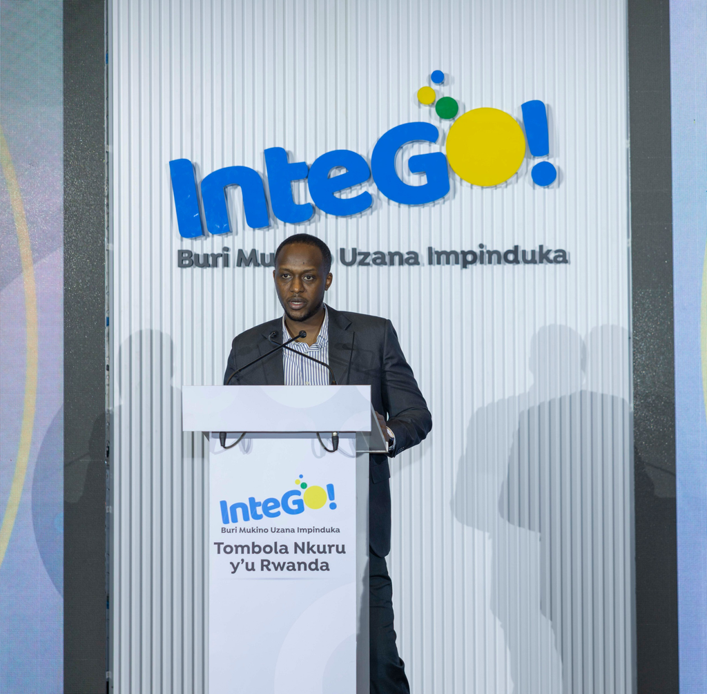 Speaker at a podium delivering a speech, with an IntegO! banner behind him.
